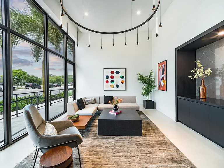 Double-height lobby lounge with floor-to-ceiling windows, curated seating, and sculptural lighting creating a bright, welcoming space to gather or unwind.