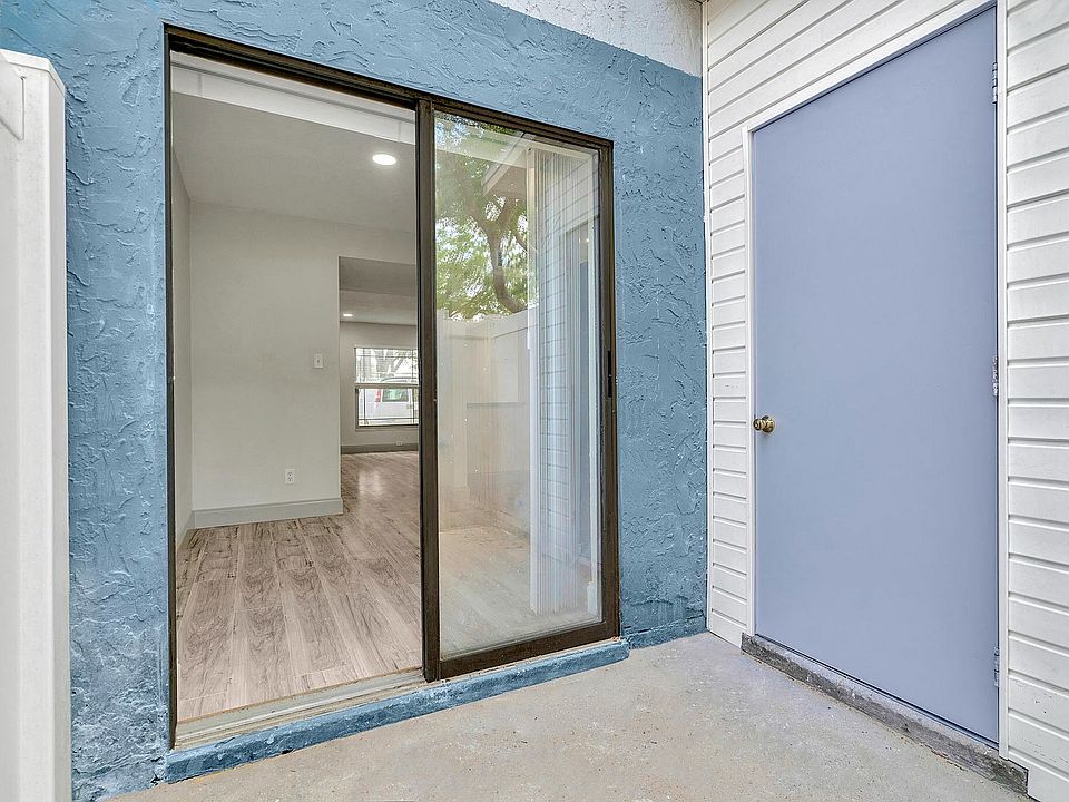 Inviting apartment entrance with modern sliding glass door opening to bright, spacious interior featuring elegant wood flooring.