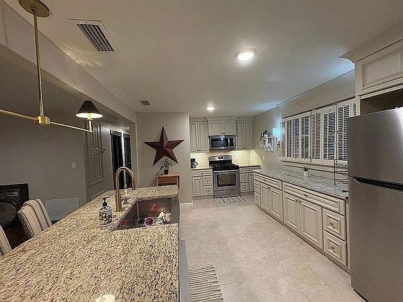 Kitchen with stainless steel appliances, light stone counters, and pendant lighting