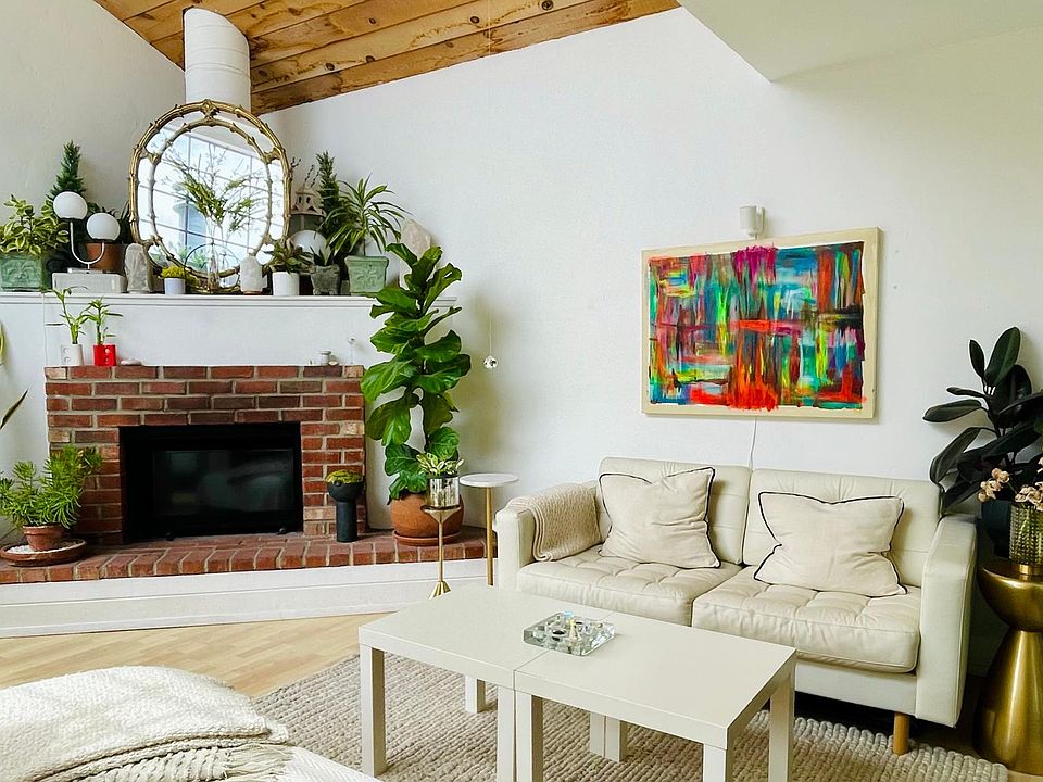 Light-filled living room with soaring vaulted ceilings, fireplace, and glass window wall