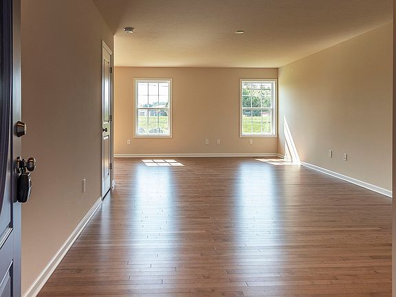 View from foyer into great room area - 2 windows on rear wall and hardwood flooring