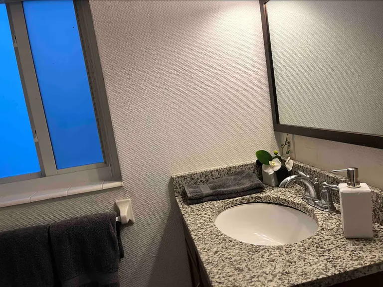 The bathroom has a granite countertop on the vanity as well as a shower with a tub for your enjoyment.