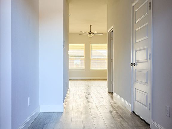 Hallway featuring wood-finish flooring, white walls, and a five-panel interior door