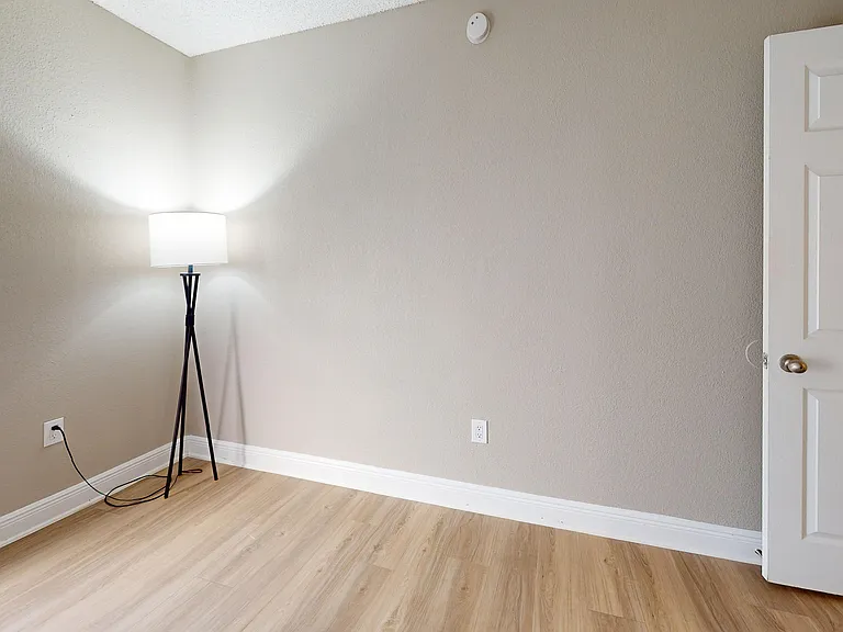 Bright and inviting room with sleek hardwood flooring and a modern floor lamp, perfect for a cozy living space.