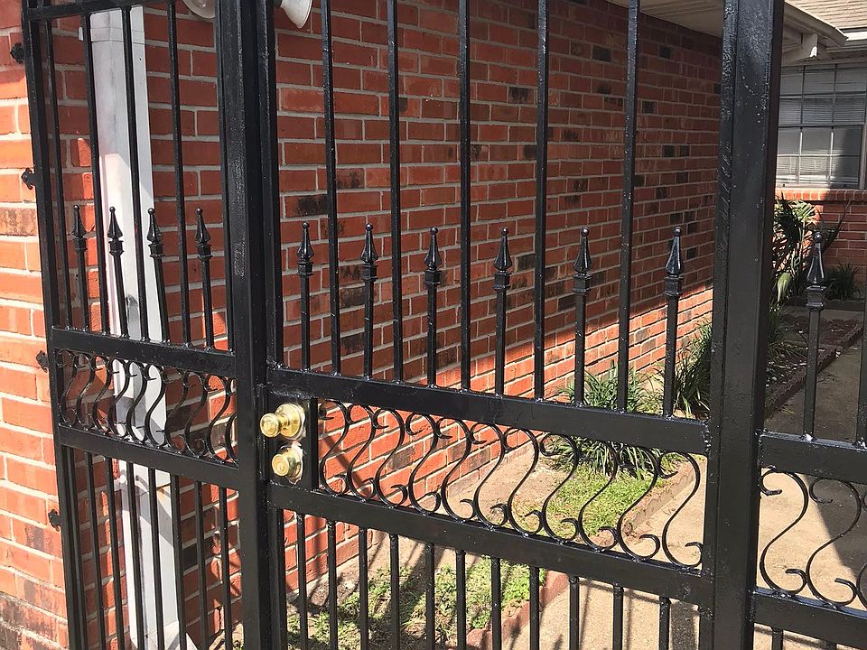Gated street entrance adjacent to garage with garden features lining walkway to the door.