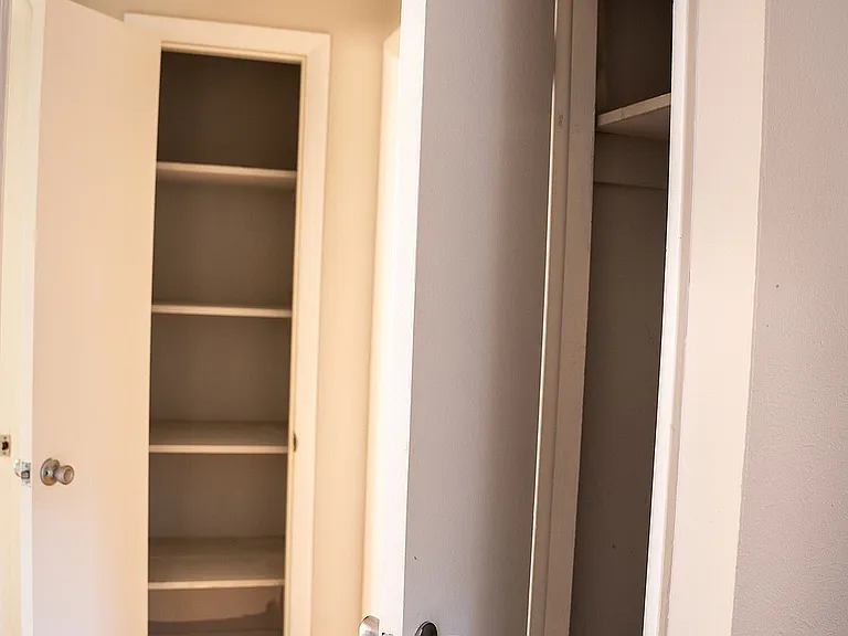 Bright hallway showcasing sleek double closets with ample storage space and elegant hardwood flooring.