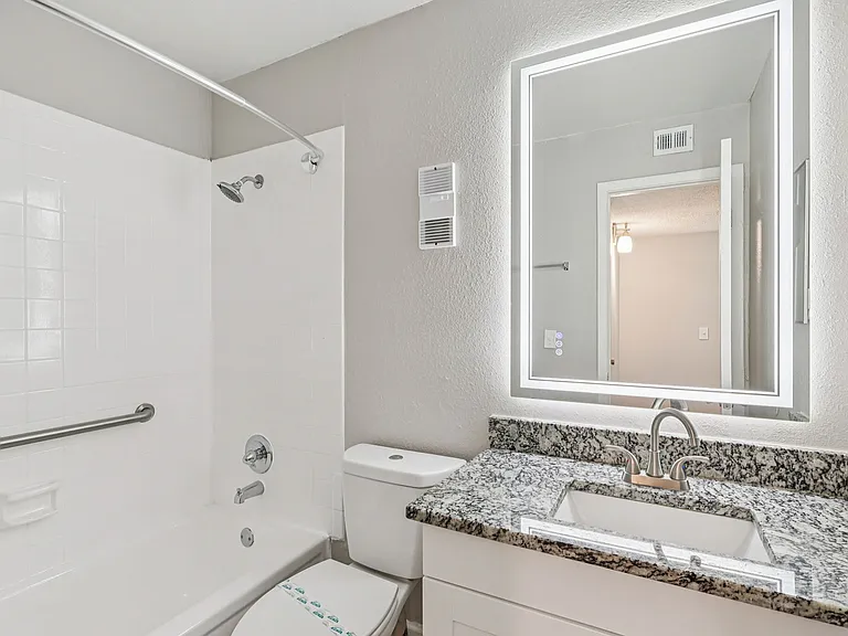 Bright bathroom with granite vanity and tub-shower combination.