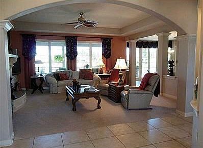 Great Room. The gas fireplace has a curved hearth, intricately designed corbels, and built in cabinetry to the right of it. This room, as well as a couple others, offer a stylish leaf ceiling fan. The staircase to the basement runs behind the back wall.