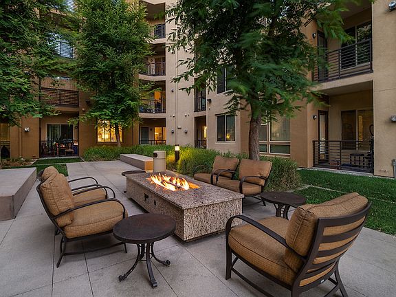 Outdoor lounge with a firepit, chairs, and a table.