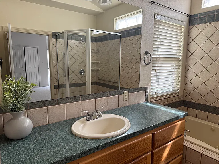 LARGE MIRROR IN THE MASTER BATHROOM. TUB HAS A JACUZZI.