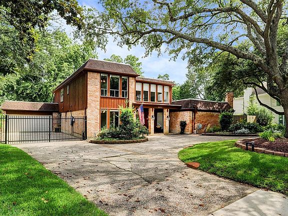 Another view showing the massive trees, garage, driveway gate & plenty of room for additional parking.
