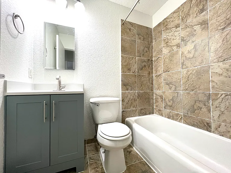 Bathroom shower/tub with medicine cabinet and vanity for storage.