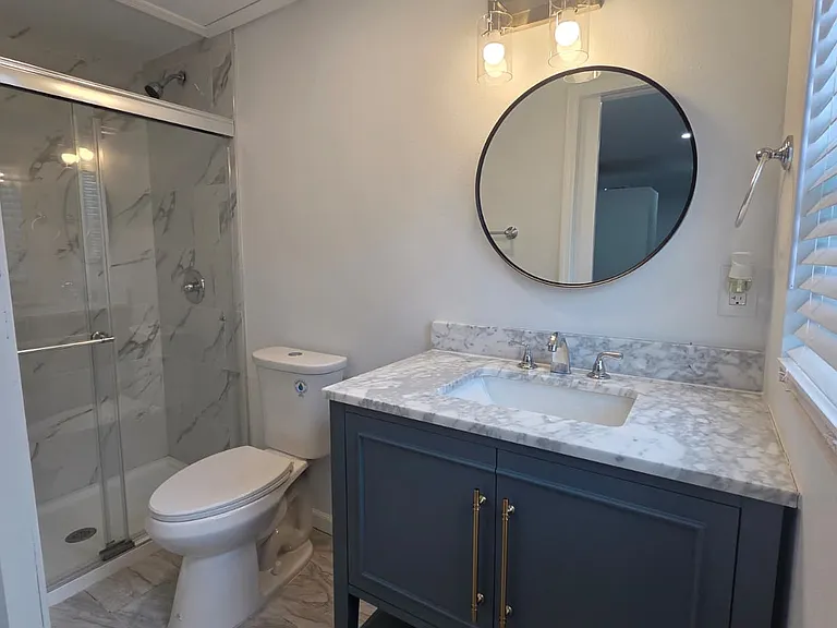 Beautiful, spotless bathroom featuring sink, toilet, shower, cabinets & mirror.