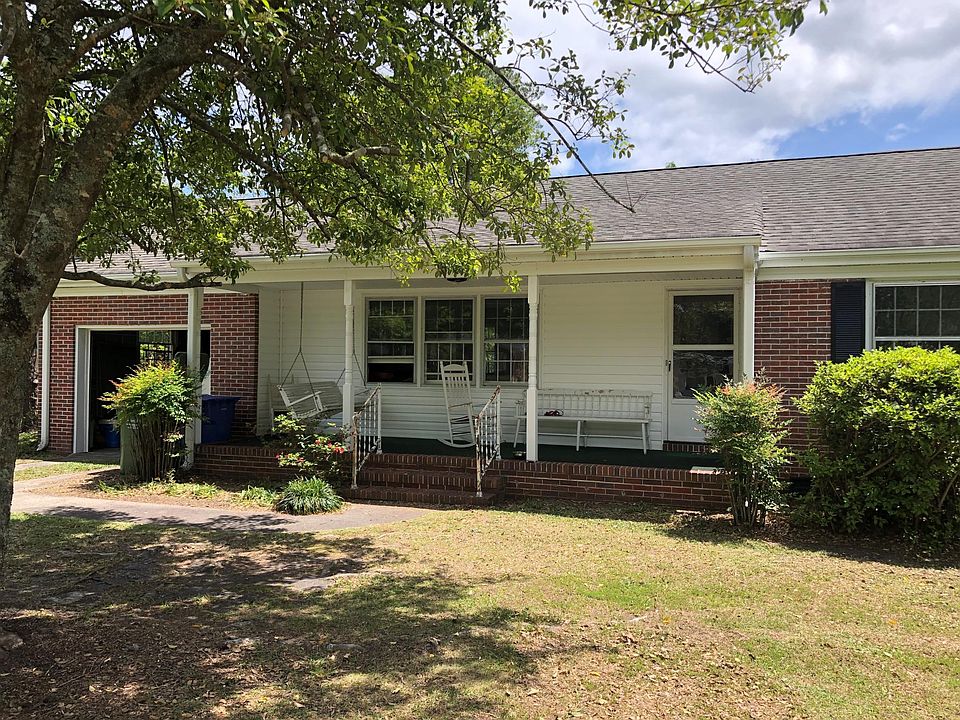 Front view of house with porchswing, rocking chairs and front door. 
Single garage with opener for storage or a small car.