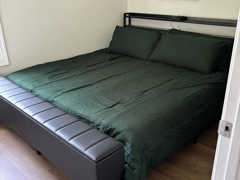 Furnished bedroom with a King bed, bench seating, and framed wall art, plus easy-care flooring and natural light.