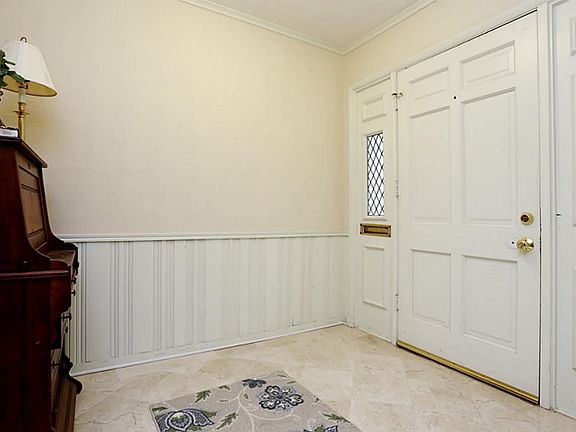 The home has a bright entrance with marble tile, wainscoting, a convenient mail slot, and a hall clo