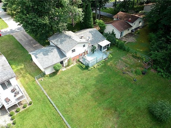Aerial view shows the back yard with almost half an acre of land, deck and enclosed porch.