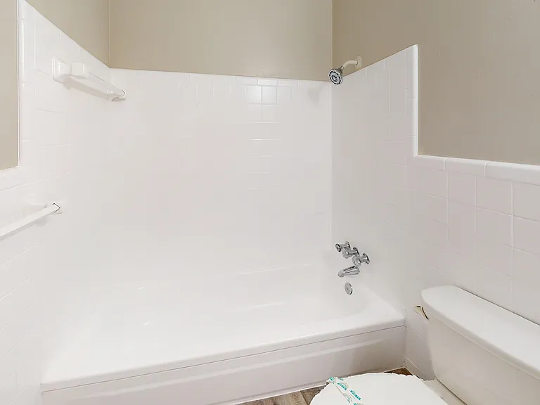 Bright and modern bathroom featuring a sleek white bathtub, tiled walls, and a convenient showerhead for a refreshing experience.