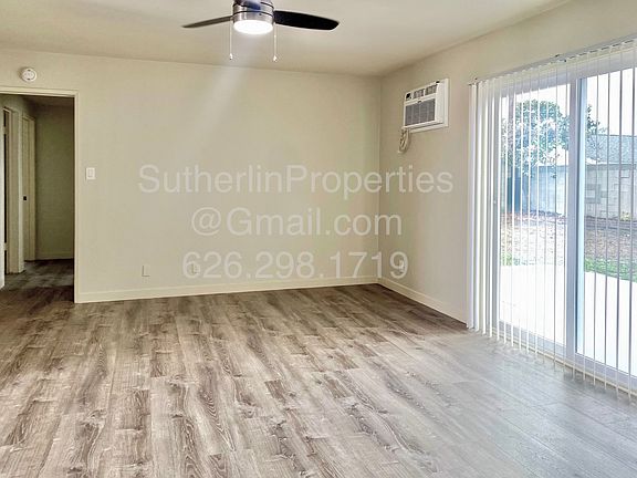 Spacious living room with new ceiling fan, new wall AC, and sliding glass doors with view over the patio and fantastic large back yard