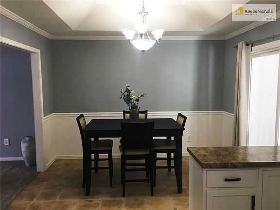 Dining area with wainscoting, a vaulted ceiling and a tile floor. The dining area walks out to an enclosed porch/sun room.