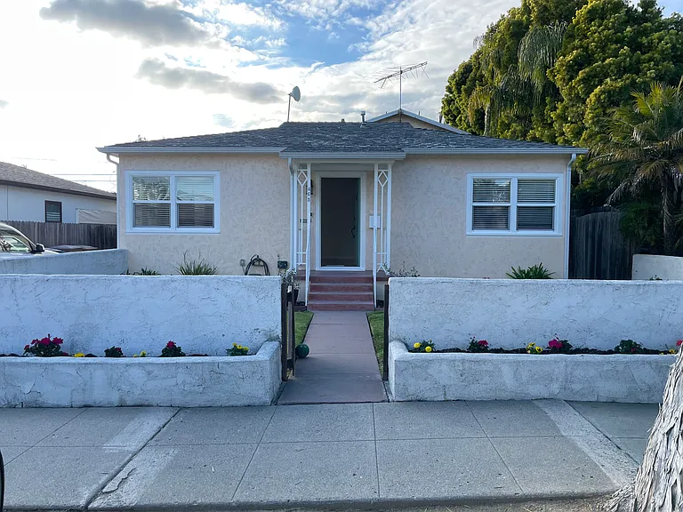 This is the street view of the front house with the parking space and entrance gate to the back house on the left.