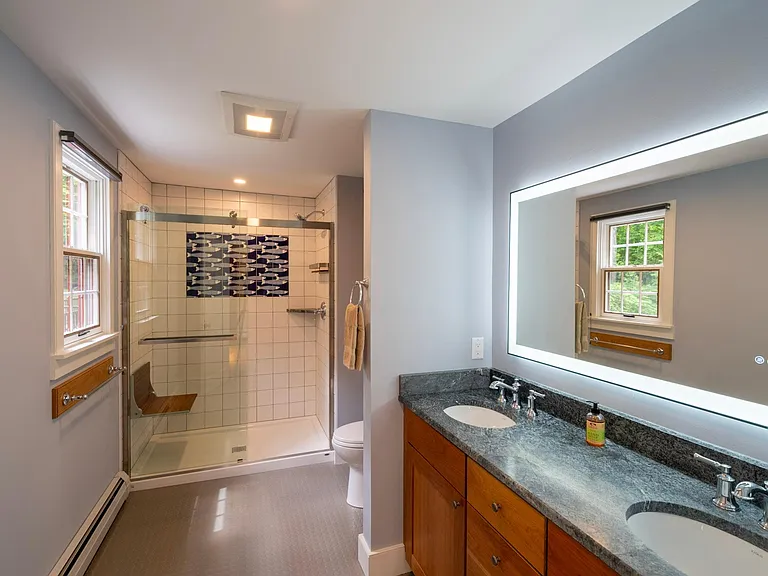 Primary bedroom bath has a walk-in shower, with bench and hand held shower head