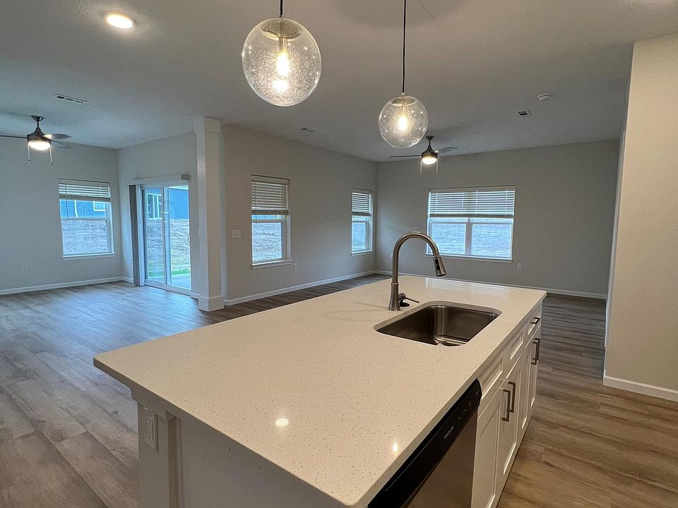 Open floor plan with quartz countertops, stainless steel appliances, custom pendant lighting, and vinyl plank flooring.
