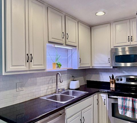 Galley kitchen with white shaker cabinets, white subway backsplash through out and stainless appliances