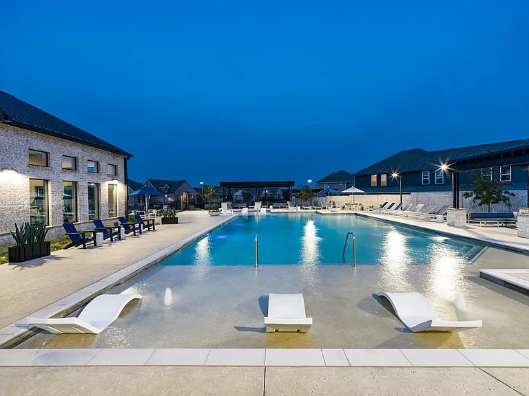 A resort-style pool at Amavi Celina with in-water loungers, expansive deck space, and evening lighting that sets the scene for relaxed nights outdoors.
