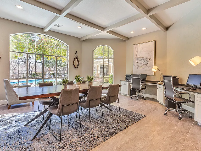 Business center boasting natural lighting and large windows with conference table, computers and printer