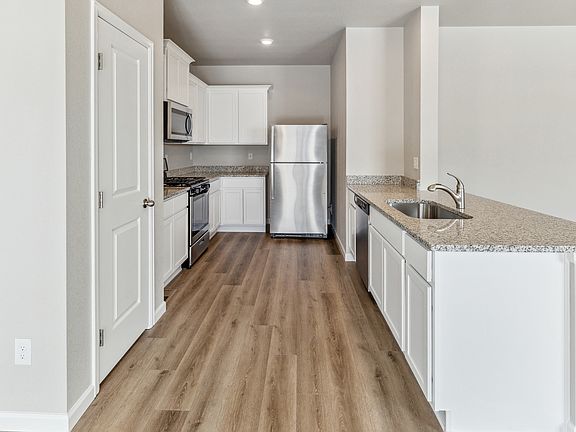 Upgraded kitchen with stainless appliances and wood-style flooring.