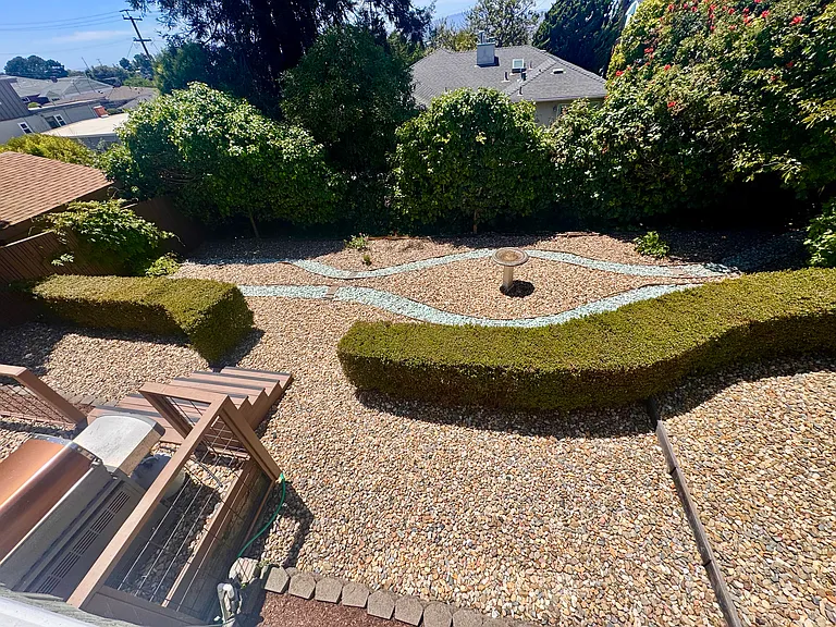 The rear garden is anchored by a traditional birdbath and two-tone low maintenance dry creek bed design with mature English boxwoods.