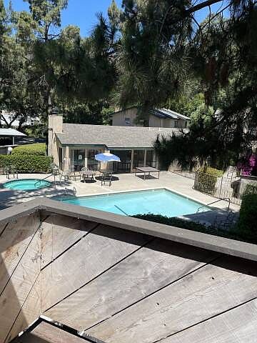 Balcony view overlooking pool house, pool, and hot tub area
