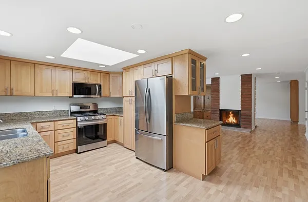 Kitchen with big skylight, dining room, living room. Dual-sided fireplace.