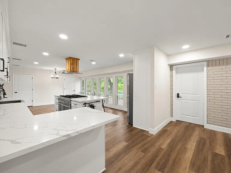 Open kitchen with large island, quartz-style counters, gas range, and ample cabinetry, plus windows overlooking the yard.