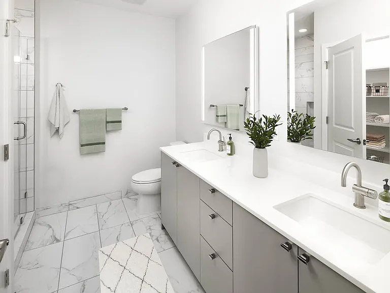 Signature Collection Townhome bathroom with grey cabinetry, white quartz countertop, lighted vanity mirrors, porcelain shower surround, and porcelain tile flooring