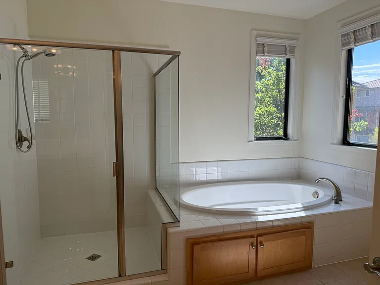 In-suite bathroom with 2 sinks, a whirlpool bathtub, a shower stall with glass enclosure and a second walk-in closet.