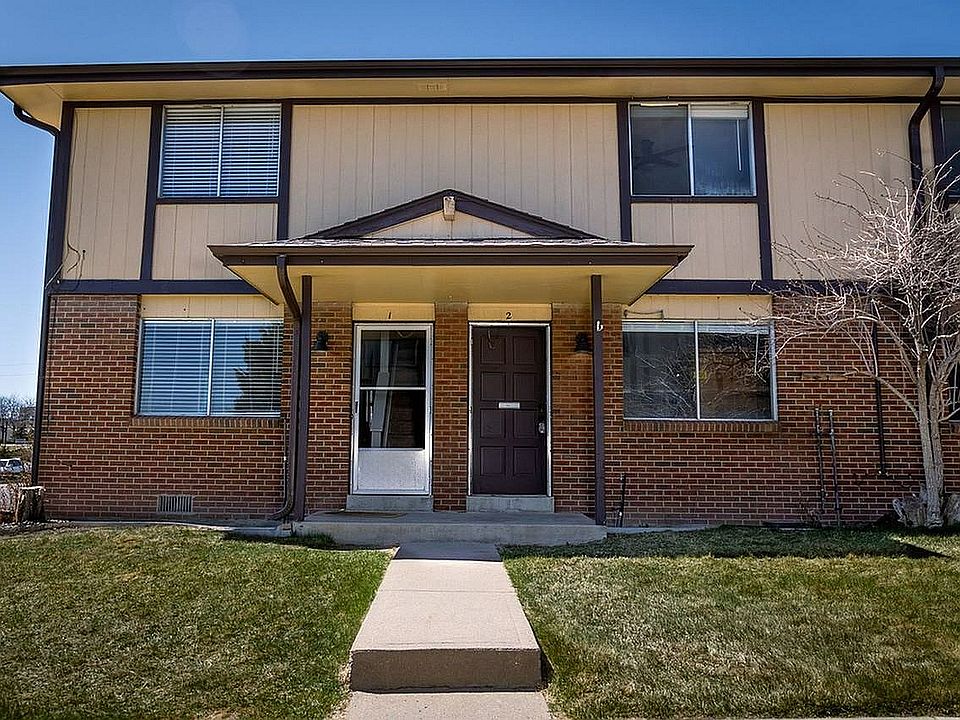 Step into comfort with this charming townhouse featuring a classic brick exterior and lush green lawn.
