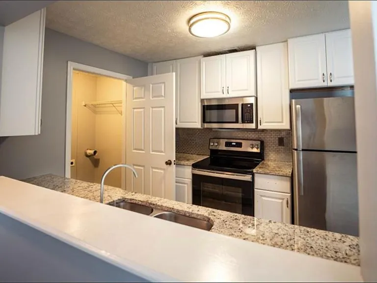Updated kitchen with granite counters, ample white cabinetry, and stainless appliances plus a double-basin sink.