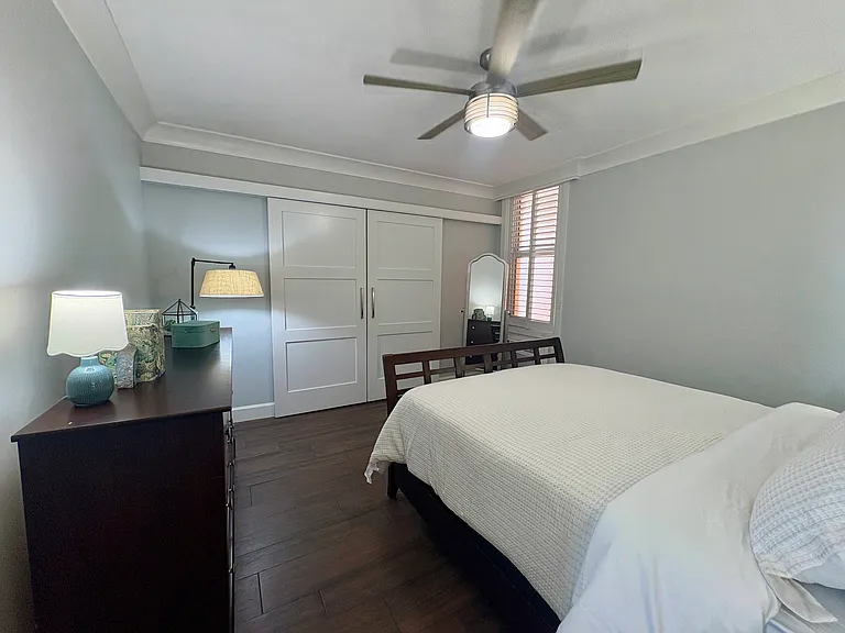 Double sliding farm doors to full width closet. Full length mirror on stand with internal storage. Window adds light and has plantation shutters for darkening.