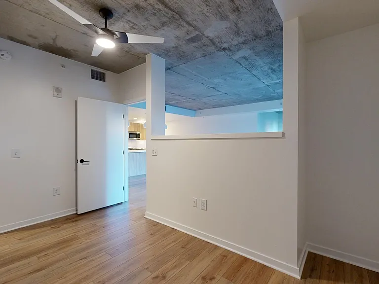 Spacious apartment bedroom with large closet, attached bathroom and wood-style flooring.