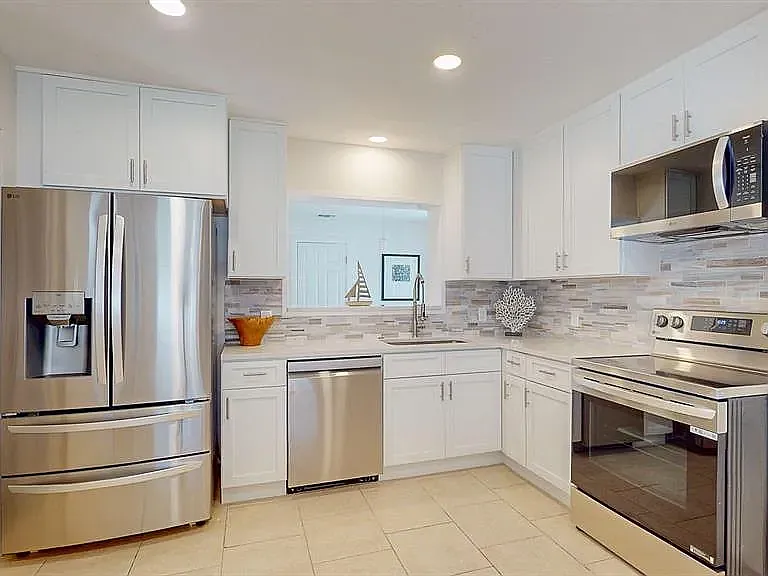 Fully remodeled kitchen with brand-new LG stainless steel appliances, white shaker cabinets, and modern tile backsplash