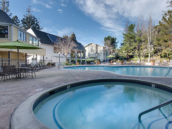 Swimming pool and spa surrounded by lounge chairs.