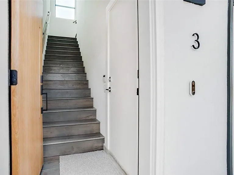 Entryway featuring a wood-finish door, white walls, and a staircase with wood-finish treads and risers