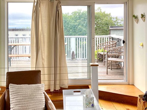Living area with light and views form private deck, wide plank floors, and exposed beams.