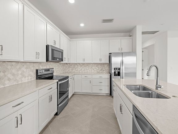 Kitchen with white cabinets, mosaic backsplash stainless steel appliances