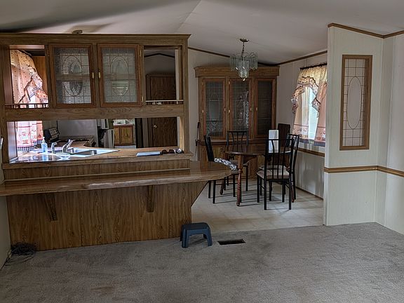 View from living room into kitchen and dining area. Home has cathedral ceilings, built in China cabinet, and glass chandelier in dining area.