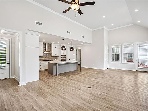 Unfurnished Family and Dining room with high vaulted ceiling, a ceiling fan, light wood-style floors