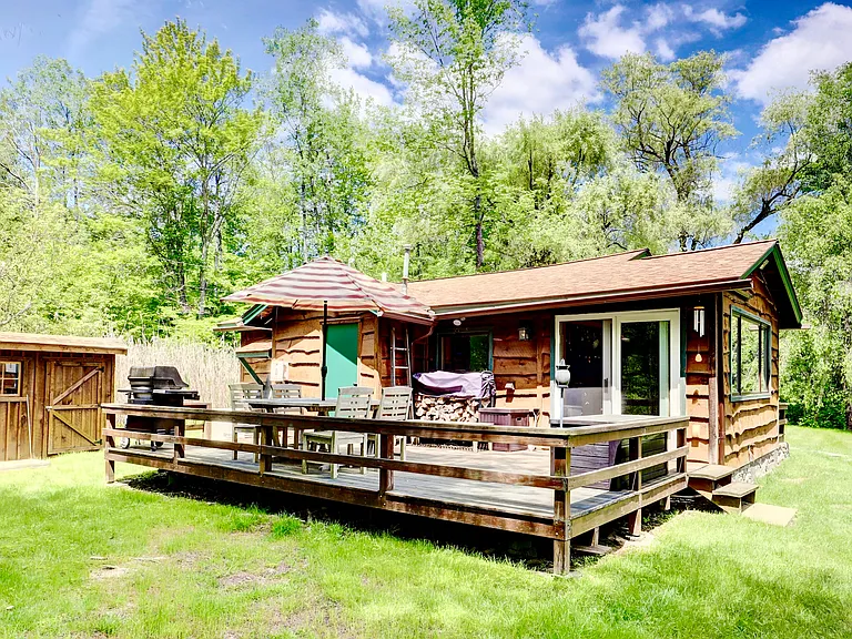 Grandview Cabin's deck with propane grill and patio furniture and with a storage shed behind.