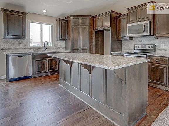Kitchen offers stainless steel appliances (microwave, dishwasher, electric range), garbage disposal, custom beech cabinetry with crown molding, granite counter tops and tiled backsplash.
